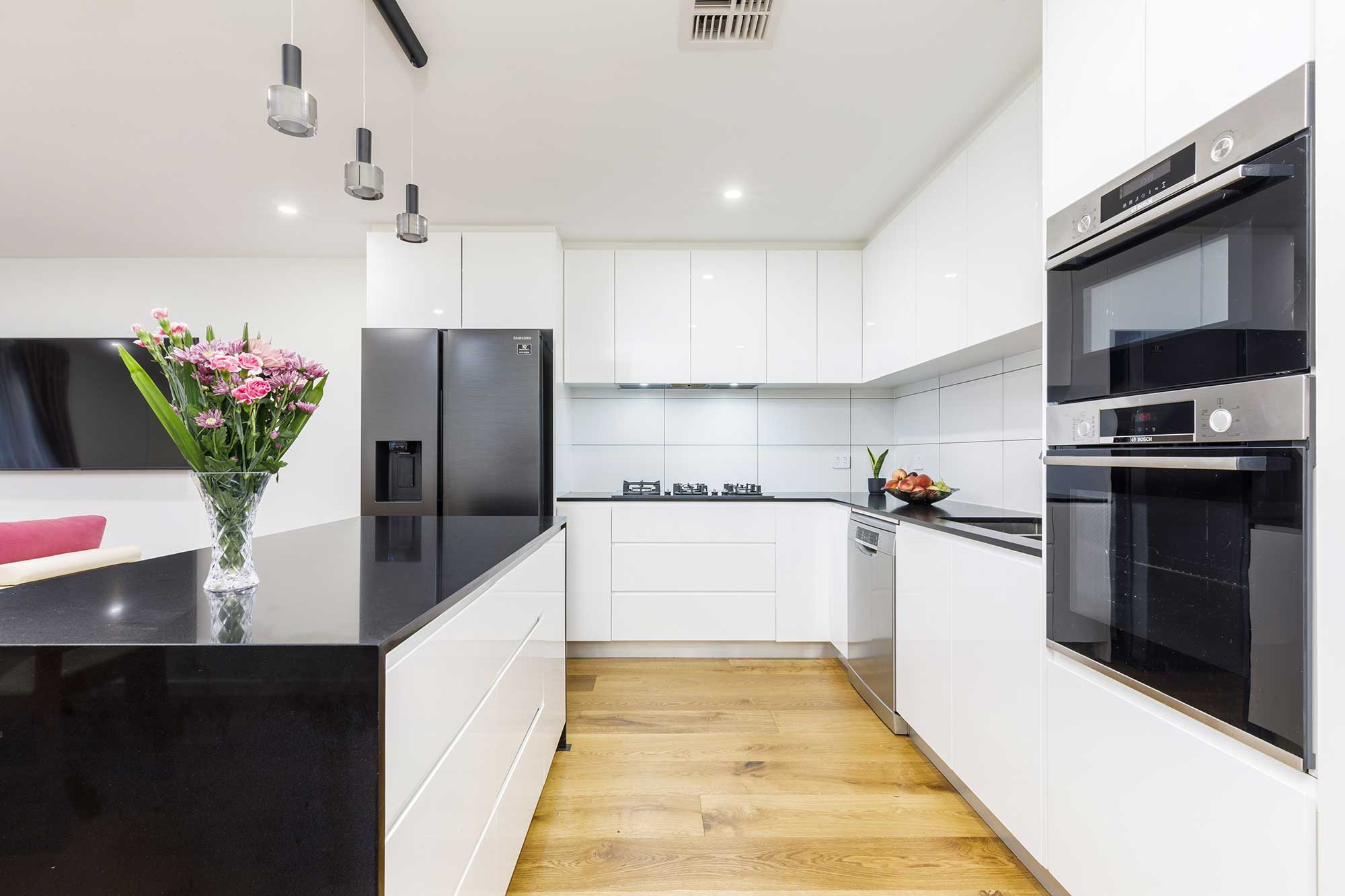 Modern white kitchen fit-out with pendant lighting, island bench and premium appliances in a Taylor, Canberra custom home by CanDo House.